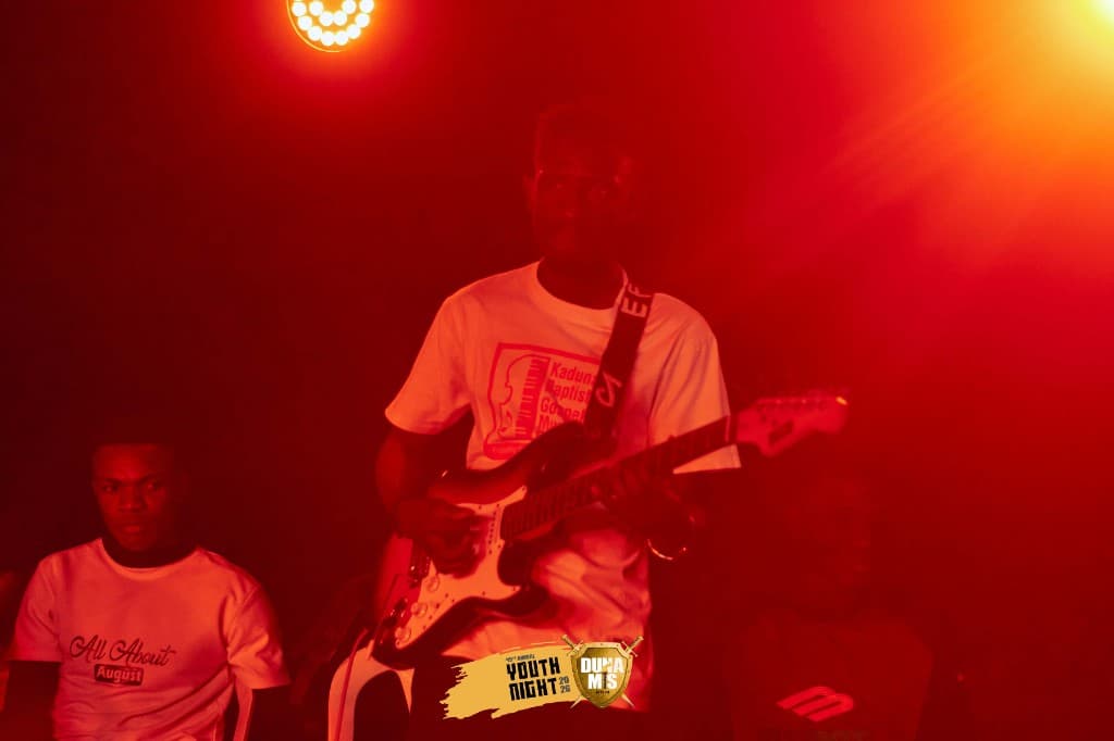 Youth Night live worship — guitarist on stage under red lights